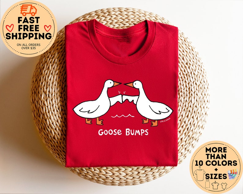 Puede incluir: Camiseta roja con un dise&ntilde;o de piel de gallina blanca. El texto "Goose Bumps" est&aacute; impreso debajo del dise&ntilde;o.