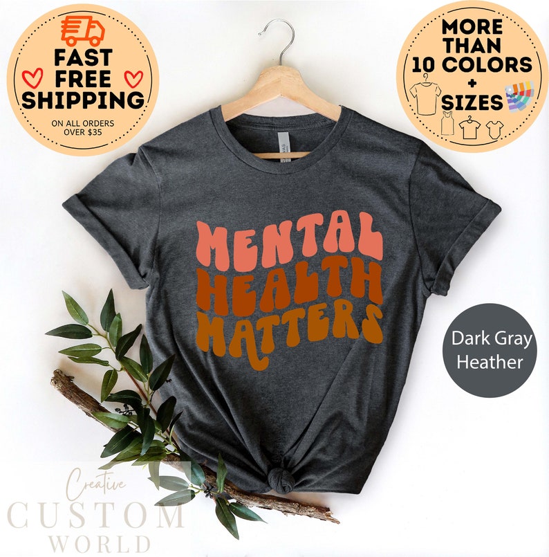 May include: Dark gray heather t-shirt with the text "MENTAL HEALTH MATTERS" in a retro, colorful font.