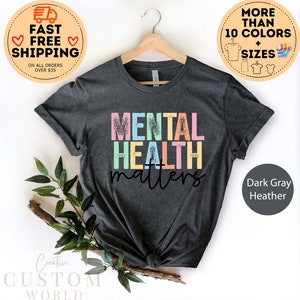 May include: Dark grey heather t-shirt with the text "MENTAL HEALTH matters" in rainbow colours. The text has a distressed, vintage look.