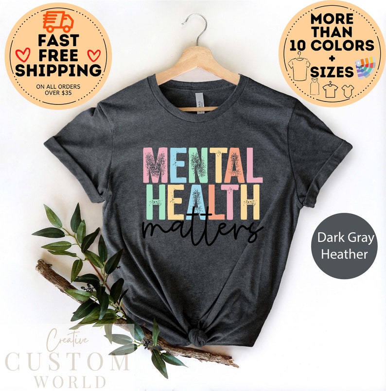 May include: Dark grey heather t-shirt with the text "MENTAL HEALTH matters" in rainbow colours. The text has a distressed, vintage look.