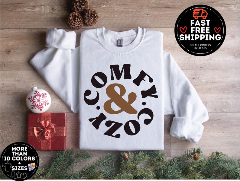 May include: White sweatshirt with a brown and black graphic that says "Comfy & Cozy" in a retro font.