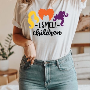 May include: White t-shirt with a graphic of three witches' silhouettes and the text "I smell children".