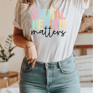 May include: White t-shirt with the text "MENTAL HEALTH matters" in rainbow colours. The text is in a distressed font style.