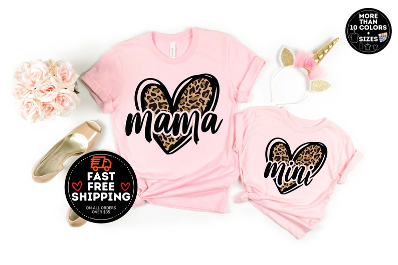 May include: Two pink t-shirts with a leopard print heart design. The larger shirt says "mama" and the smaller shirt says "mini".