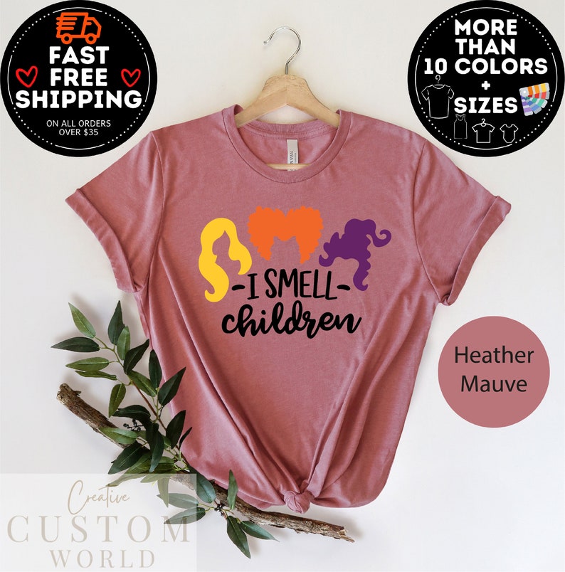 May include: A heather mauve t-shirt with a graphic of three witches with the text "I Smell Children".