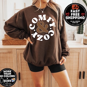 May include: Brown sweatshirt with white text that reads "Comfy & Cozy" in a retro font.