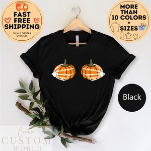 May include: Black t-shirt with a graphic of two orange pumpkins with skeleton hands. The text "More Than 10 Colors + Sizes" is in a circle above the shirt. The text "Black" is in a circle below the shirt.