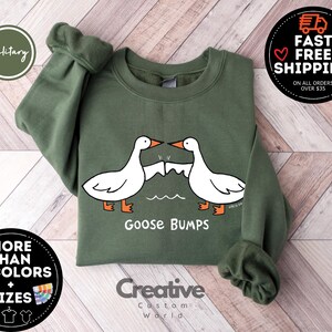 Puede incluir: Una sudadera verde con un dise&ntilde;o de piel de gallina blanca y el texto "Goose Bumps".