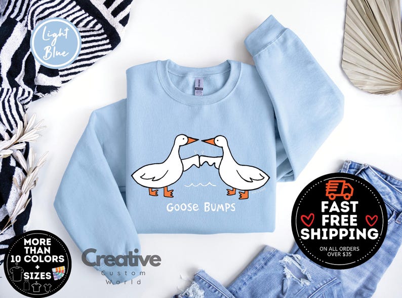 Puede incluir: Sudadera azul claro con un gr&aacute;fico de dos gansos que se miran con el texto "Goose Bumps".