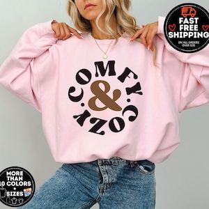 May include: Pink sweatshirt with a black and brown graphic that says "Comfy & Cozy" in a circle.