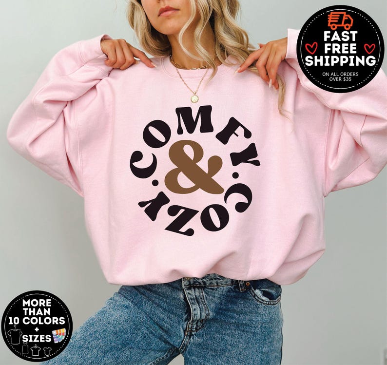 May include: Pink sweatshirt with a black and brown graphic that says "Comfy & Cozy" in a circle.