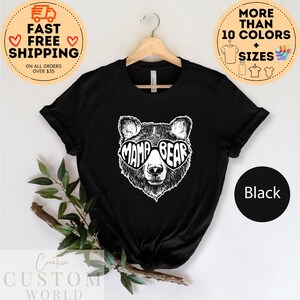Puede incluir: Camiseta negra con un gr&aacute;fico blanco de un oso con gafas de sol en forma de coraz&oacute;n que dicen "Mama Bear".