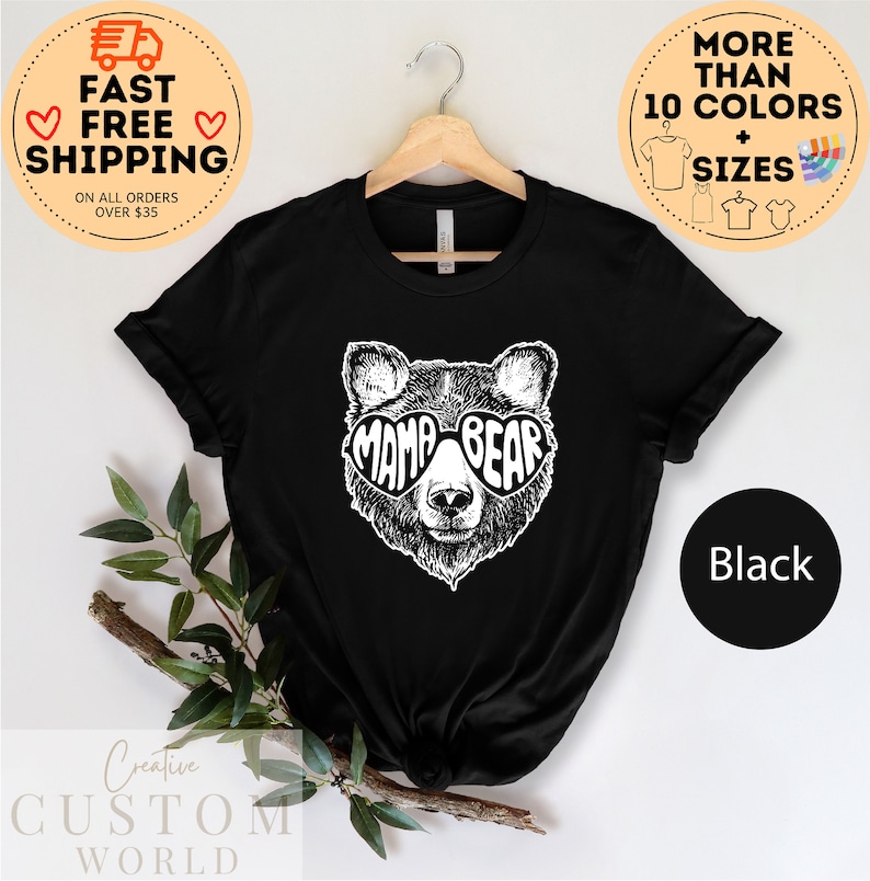 Puede incluir: Camiseta negra con un gr&aacute;fico blanco de un oso con gafas de sol en forma de coraz&oacute;n que dicen "Mama Bear".