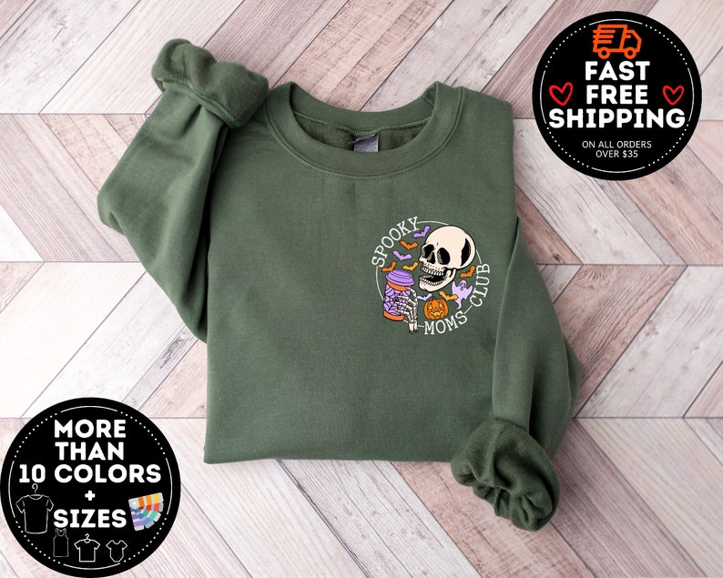 May include: Green sweatshirt with a graphic of a skull holding a potion with the text "Spooky Moms Club".