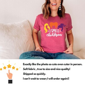 May include: A pink t-shirt with a graphic of three witches and the text "I Smell Children".