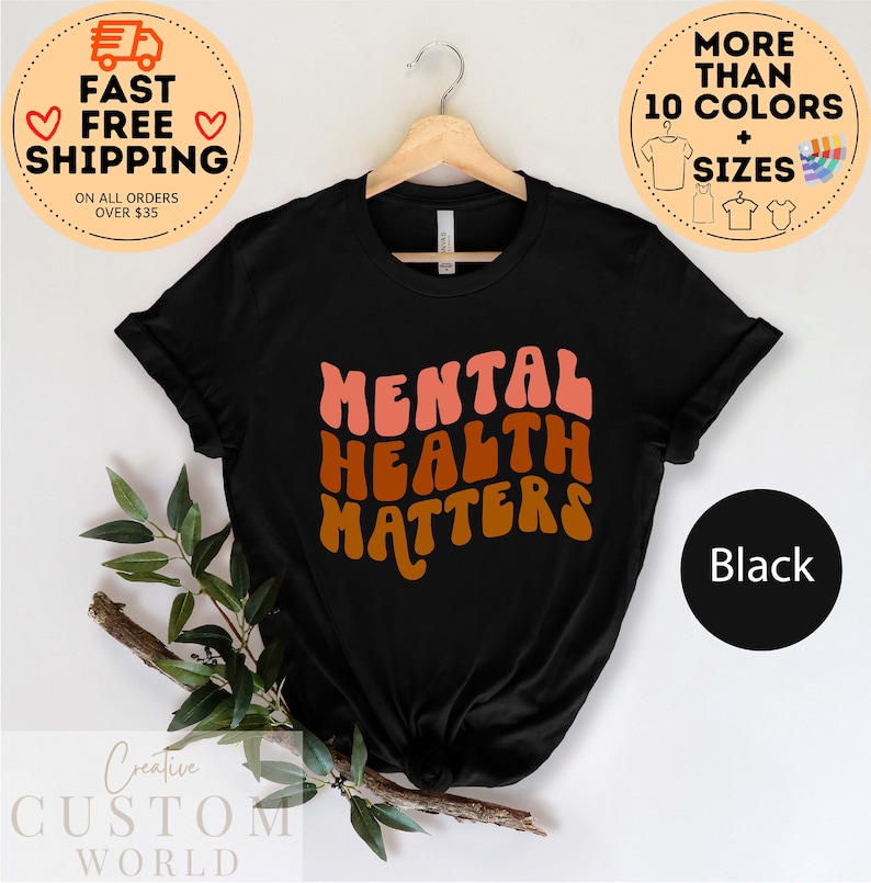 May include: Black t-shirt with the text "MENTAL HEALTH MATTERS" in a retro font with pink, orange, and brown colors.