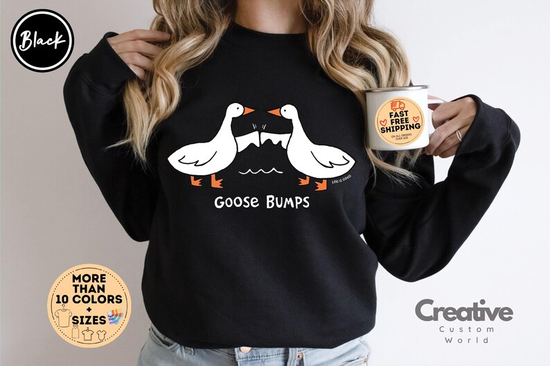 Puede incluir: Sudadera negra con un gr&aacute;fico de dos gansos que se miran con el texto "Goose Bumps".