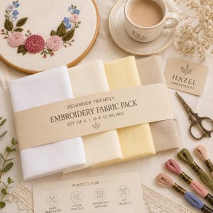 Puede incluir: Un conjunto de cuatro cuadrados de tela para bordar de 30,5 x 30,5 cm en blanco, crema, amarillo pálido y beige, envueltos en una banda de papel con la etiqueta Beginner Friendly Embroidery Fabric Pack. Incluye un bastidor con flores y hilo.