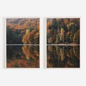 以下が含まれることがあります： 秋の紅葉した木々を映し出す湖の写真が2枚、額縁に入っています。木々は緑、黄色、オレンジ、赤と様々な色に染まっています。水面は穏やかで静かで、木々の鏡のような反射を作り出しています。
