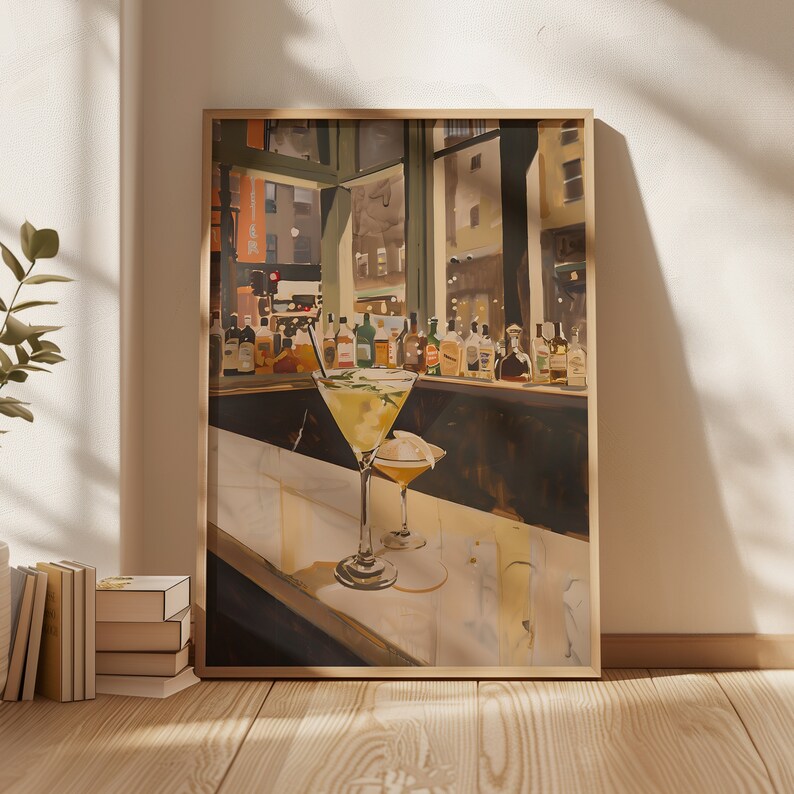 May include: A framed painting of a bar scene with two cocktails on the counter. The cocktails are in martini glasses and are filled with a yellow liquid. The bar is lit by warm, yellow light. There are bottles of liquor behind the counter.