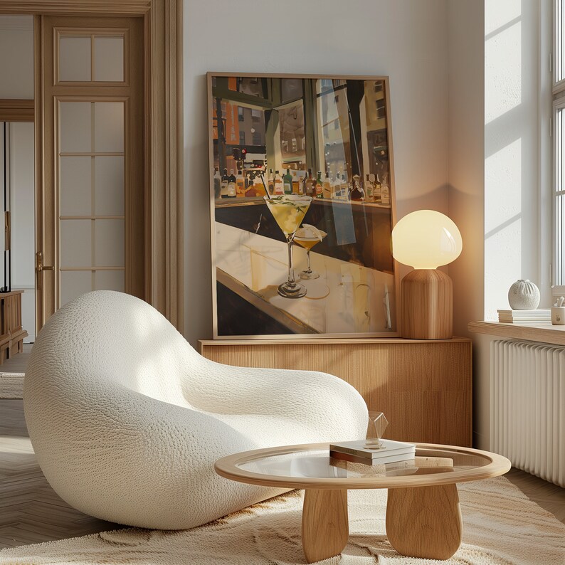 May include: A white, plush armchair with a textured surface sits in a living room with a wooden coffee table and a lamp with a white glass shade. A framed print of a bar scene with a martini glass hangs on the wall.