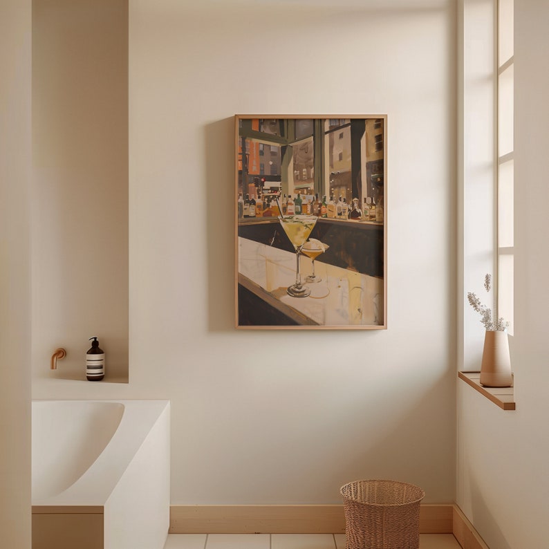 May include: A framed painting of a bar scene with two martini glasses on the counter. The painting is in a light wood frame and is hanging on a white wall.