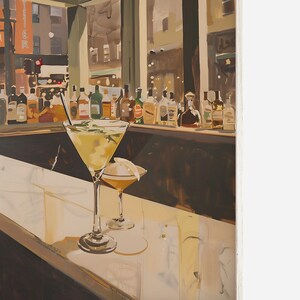 May include: Two martini glasses filled with a yellow liquid sit on a bar counter. The glass on the left has a sprig of rosemary in it. The bar is lined with bottles of liquor. The background is a blurry view of a city street.