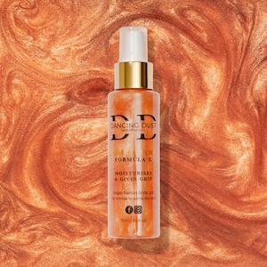 Könnte beinhalten: Eine durchsichtige Flasche mit goldener Kappe und goldener Etikette. Auf dem Etikett steht "Dancing Dust Grip Products" und "Made Me Dewy Formula X Moisturizes & Gives Grip". Die Flasche hat ein Fassungsvermögen von 100 ml (3,38 fl oz).
