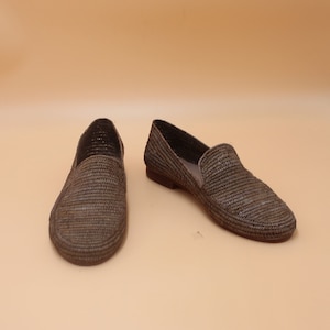 K&ouml;nnte beinhalten: Ein Paar geflochtene Strohslipp-on-Schuhe in Braun und Grau.