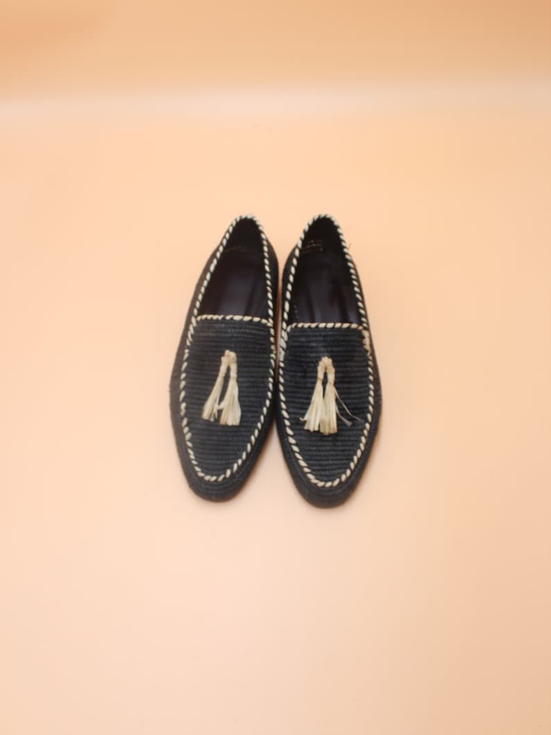 K&ouml;nnte beinhalten: Ein Paar schwarze geflochtene Lederschuhe mit Quaste. Die Schuhe haben eine wei&szlig;e Naht an den R&auml;ndern.