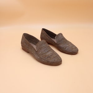 K&ouml;nnte beinhalten: Ein Paar braune geflochtene Lederschuhe. Die Schuhe haben eine spitze Zehenpartie und eine flache Sohle.