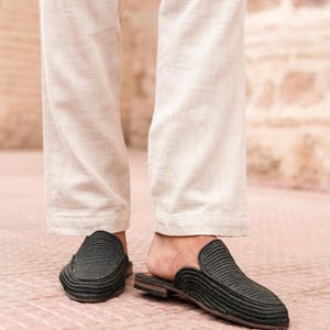 May include: A pair of black woven leather slip-on shoes with a pointed toe.