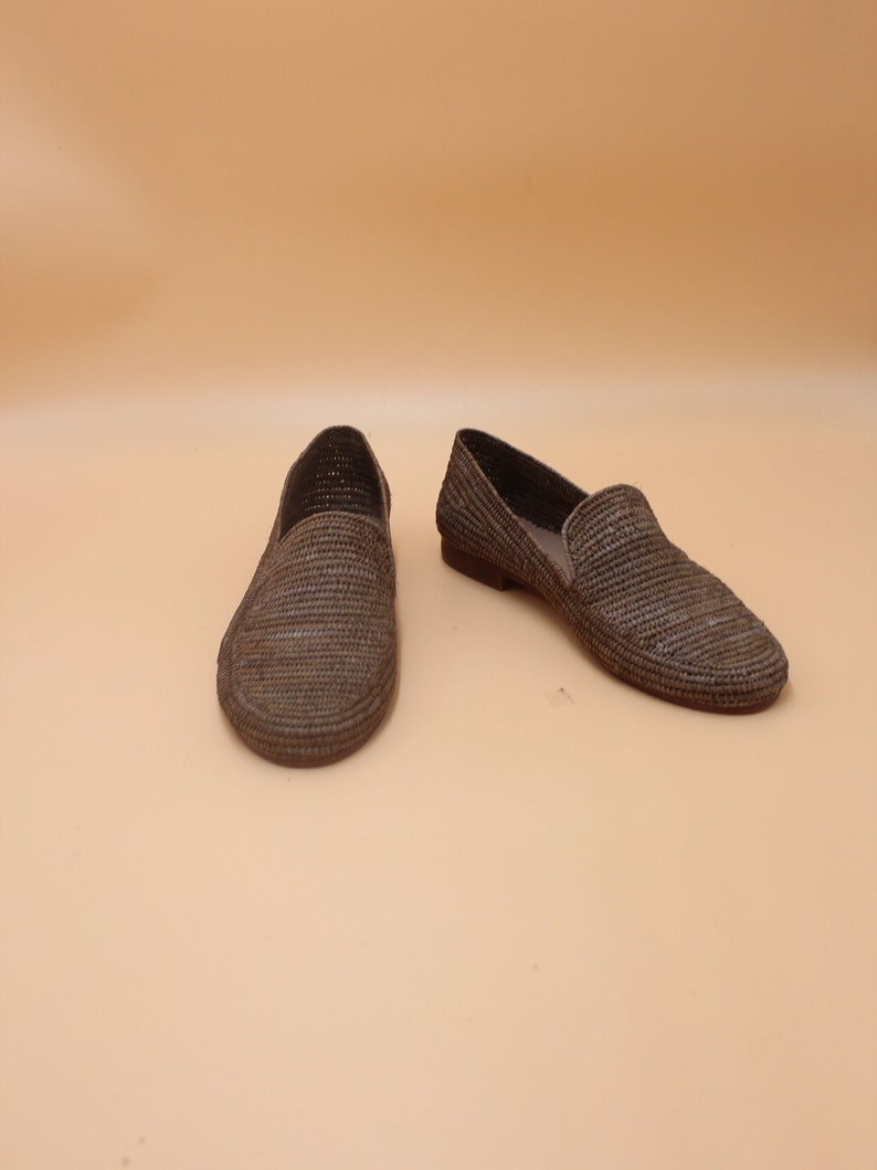 K&ouml;nnte beinhalten: Ein Paar geflochtene Strohslipp-on-Schuhe in Braun und Grau.