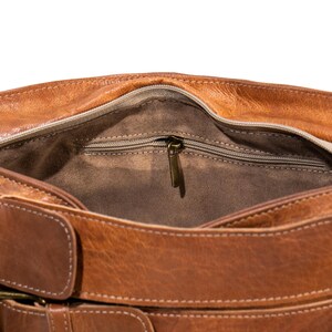 Pu&ograve; includere: Una borsa a tracolla in pelle marrone con una tasca con cerniera all'interno e una chiusura a fibbia. La borsa ha una tracolla in pelle marrone.