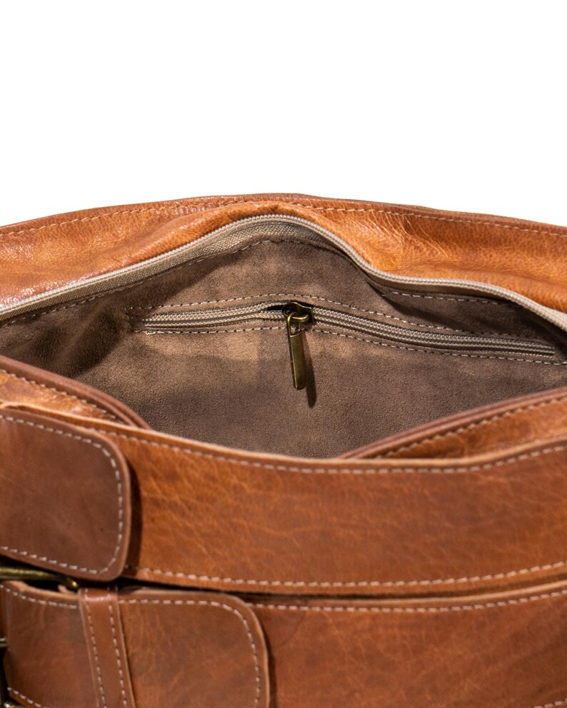 Pu&ograve; includere: Una borsa a tracolla in pelle marrone con una tasca con cerniera all'interno e una chiusura a fibbia. La borsa ha una tracolla in pelle marrone.