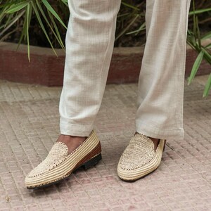 Puede incluir: Un par de mocasines de paja trenzada con suelas de cuero marr&oacute;n. Los mocasines son usados por una persona que lleva pantalones de color claro.