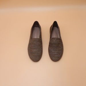 K&ouml;nnte beinhalten: Ein Paar braune geflochtene Lederschuhe. Die Schuhe haben ein schlichtes Design und sind aus einem nat&uuml;rlichen Material gefertigt.