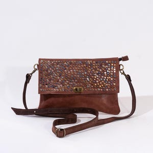 Può includere: Una borsa a tracolla in pelle marrone con chiusura a lembo e un design decorativo di strass iridescenti. La borsa ha una lunga tracolla regolabile.