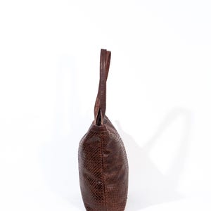 Puede incluir: Un bolso tote de cuero marr&oacute;n con estampado de piel de serpiente.
