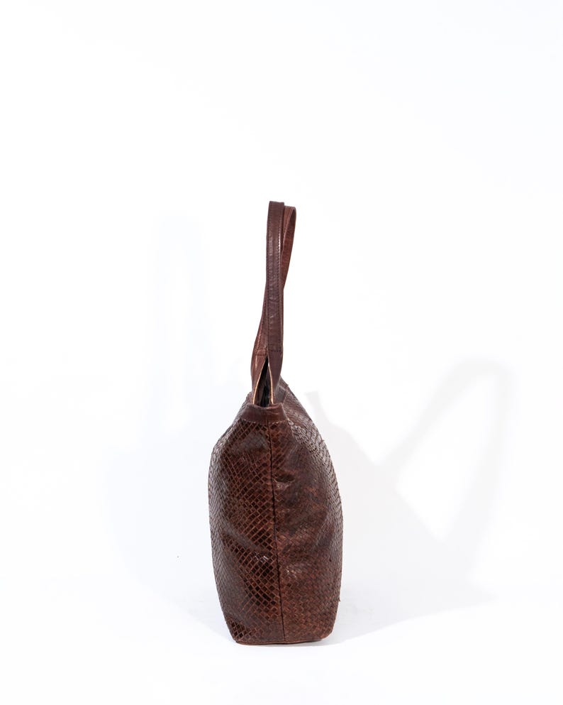 Puede incluir: Un bolso tote de cuero marr&oacute;n con estampado de piel de serpiente.