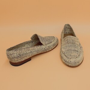 Pode incluir: Um par de mocassins de palha tran&ccedil;ada com acabamento preto. Os mocassins t&ecirc;m uma sola plana e uma ponta pontiaguda.