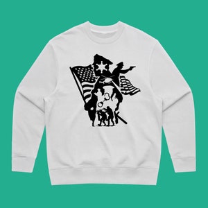 K&ouml;nnte beinhalten: Wei&szlig;er Pullover mit einem schwarzen Silhouetten-Design eines Polizisten, Soldaten und einer amerikanischen Flagge.
