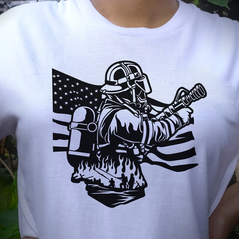 May include: Black and white illustration of a firefighter holding a hose in front of an American flag. The firefighter is wearing a helmet and a gas mask. The illustration is on a white t-shirt.