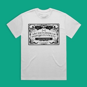 May include: White t-shirt with a black and white graphic of a Ouija board with the text "YES", "NO", "GOODBYE", "ABCDEFGHIJKLMNOPQRSTUVWXYZ", and "1234567890".