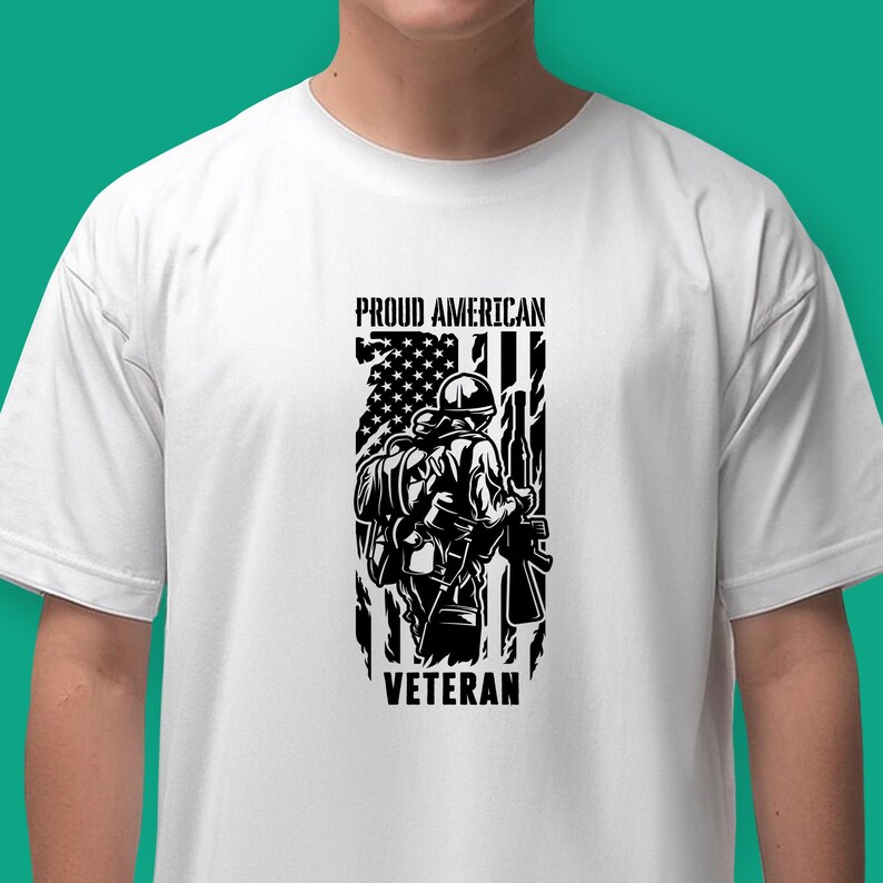 May include: White t-shirt with a black and white graphic of a soldier standing in front of an American flag. The text "Proud American Veteran" is printed on the shirt.