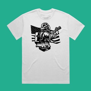 May include: A white t-shirt with a black and white illustration of a firefighter wearing a helmet and holding a hose. The firefighter is standing in front of an American flag.