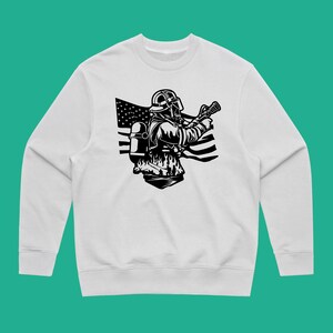 May include: White sweatshirt with a black and white illustration of a firefighter holding a hose in front of an American flag.