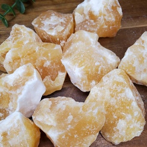 May include: A collection of raw, yellow calcite crystals. The crystals are rough and have a natural, earthy look. They are perfect for crystal healing or decoration.