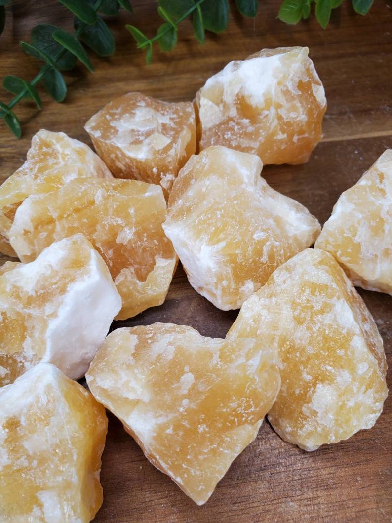 May include: A collection of raw, yellow calcite crystals. The crystals are rough and have a natural, earthy look. They are perfect for crystal healing or decoration.
