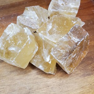 May include: A group of seven translucent, honey-colored calcite crystals. The crystals are rough and have a natural, unpolished finish.
